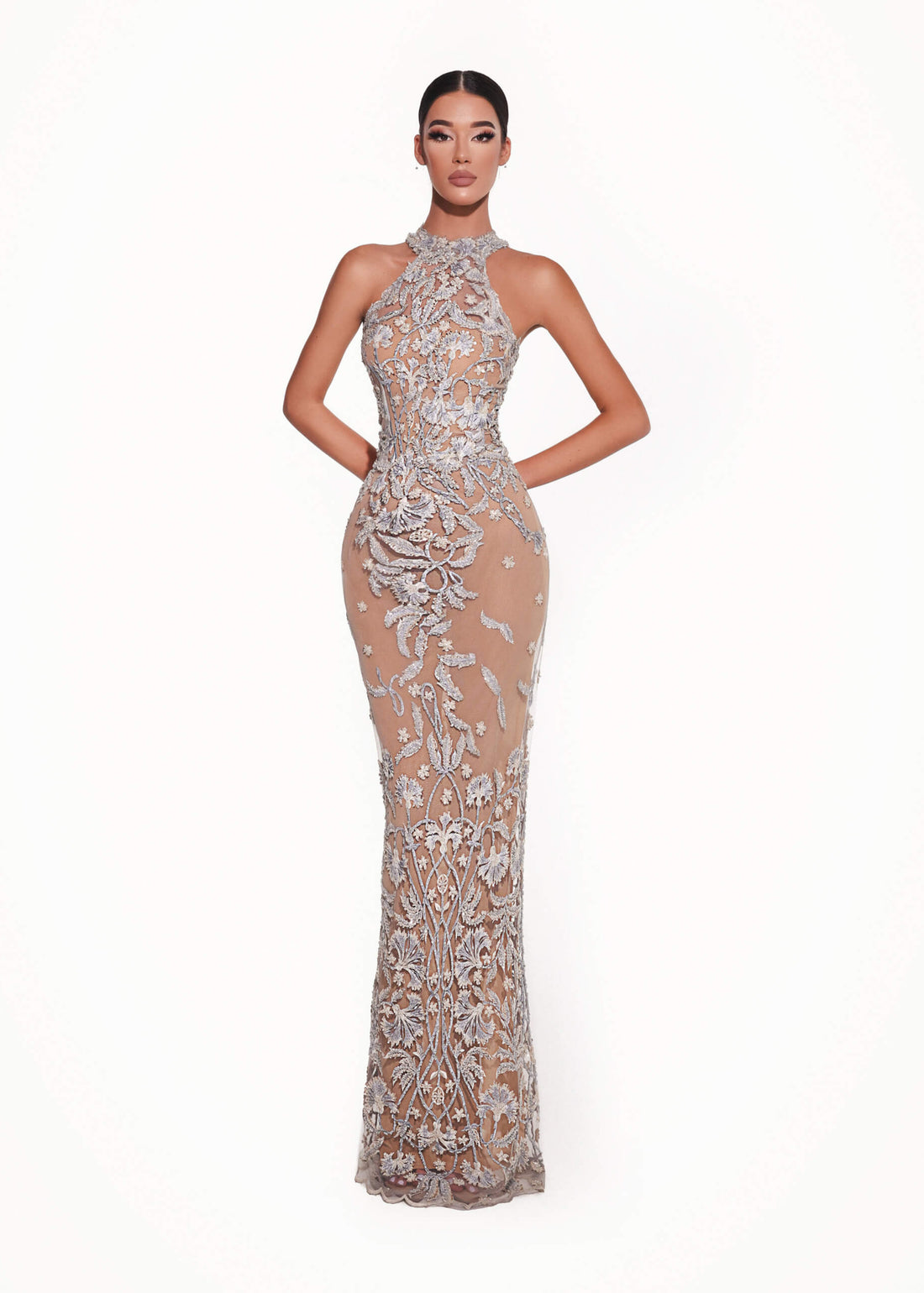 Woman wearing a silver evening gown with floral embellishments on a white background