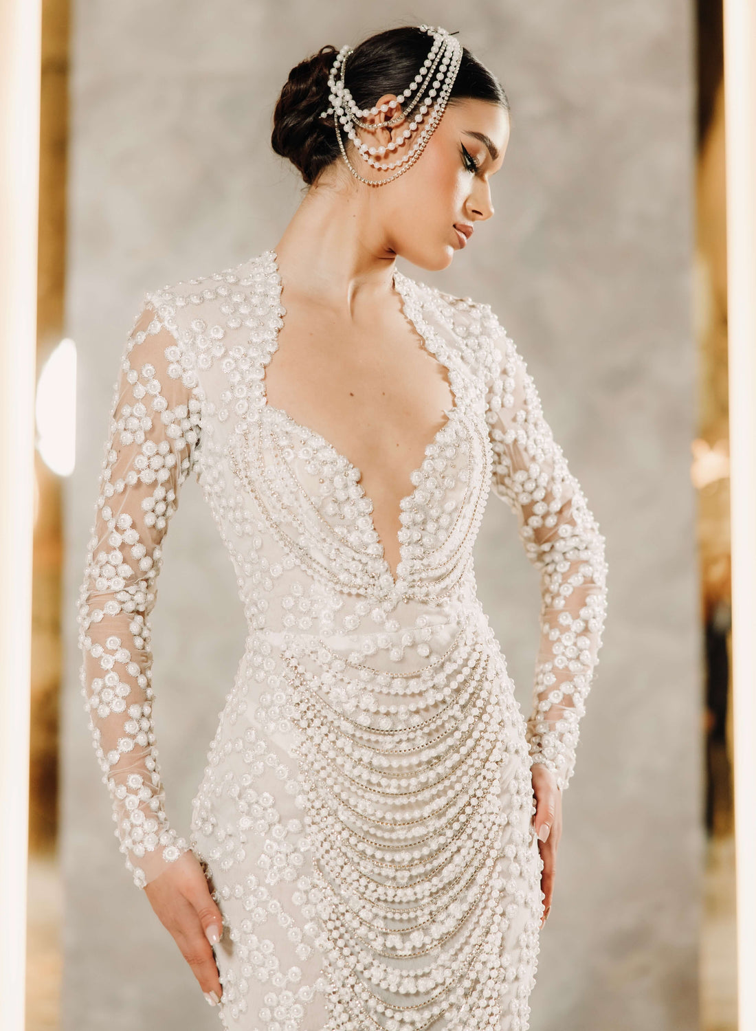 Woman wearing a beaded wedding dress with a neutral background