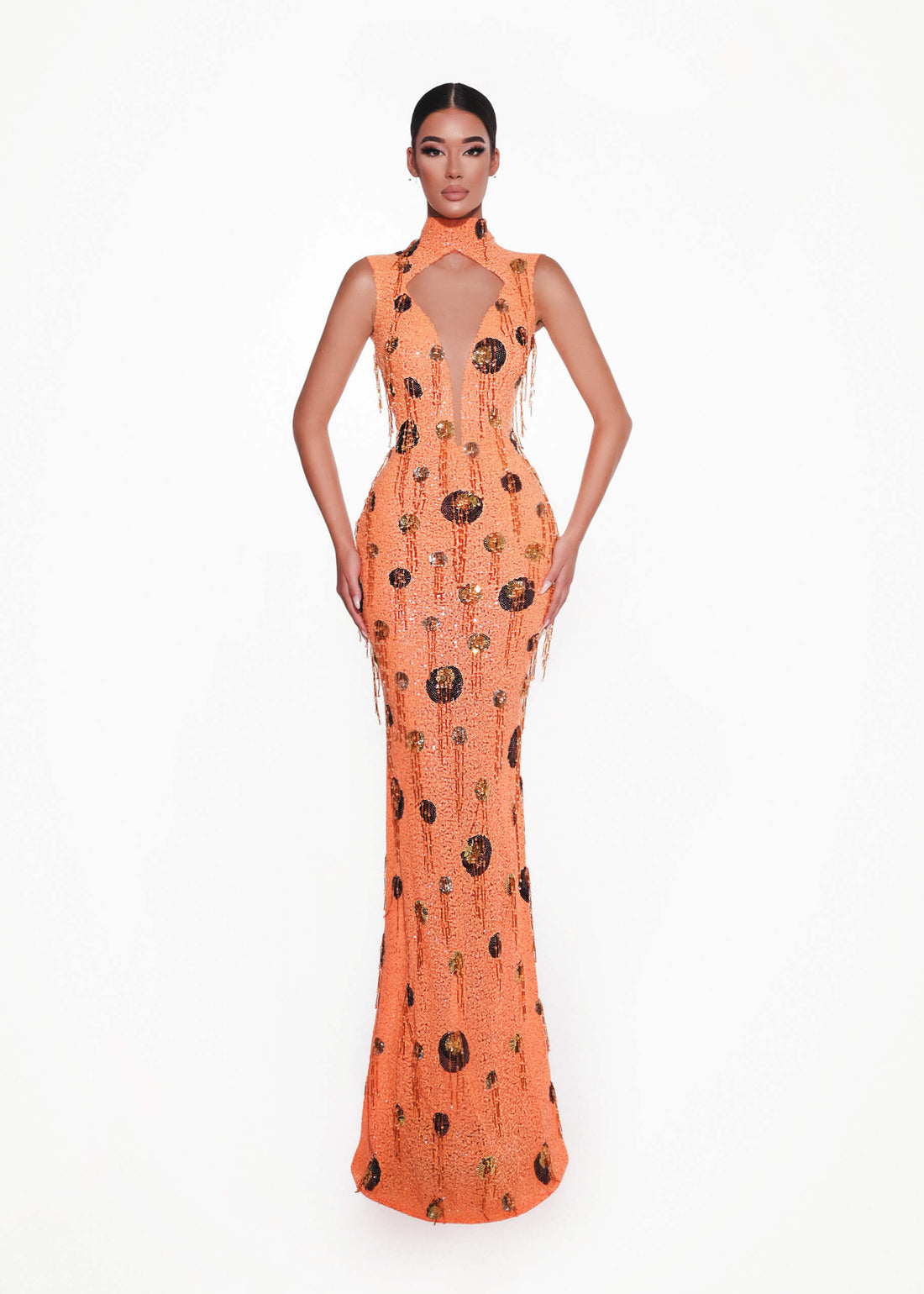 Woman wearing an orange evening couture gown with black pattern on a white background 