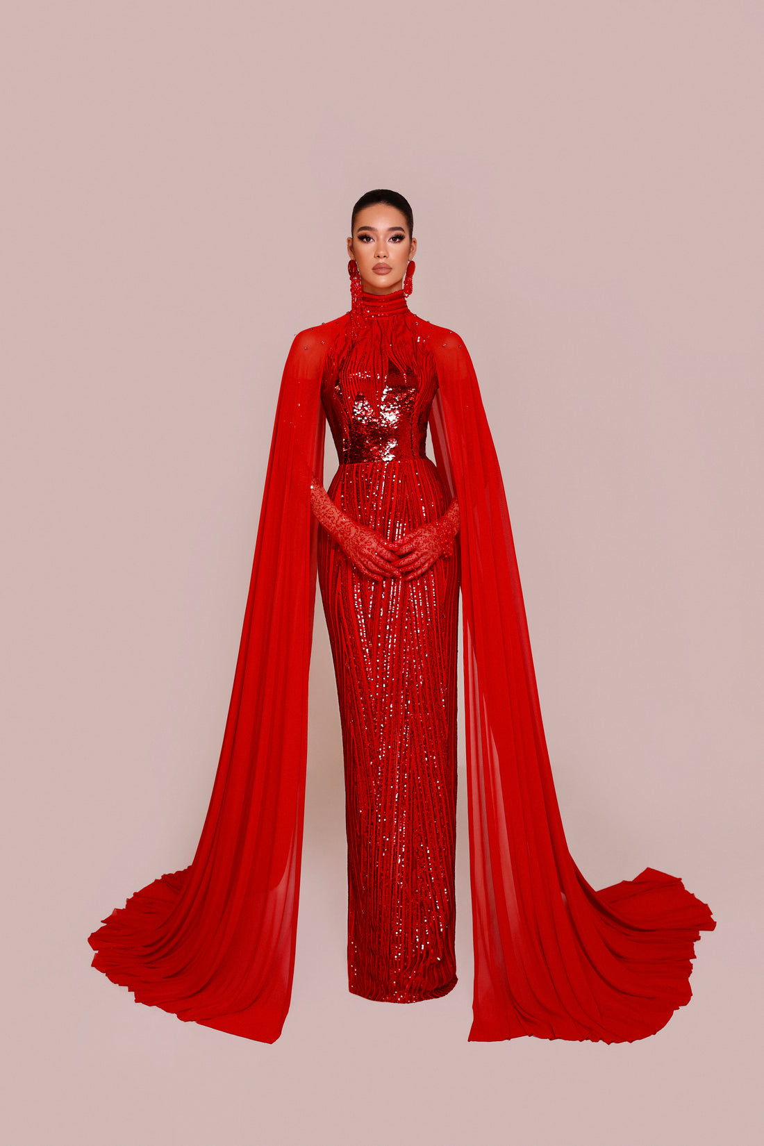 High neck red couture gown with embellished bodice and long flowing cape