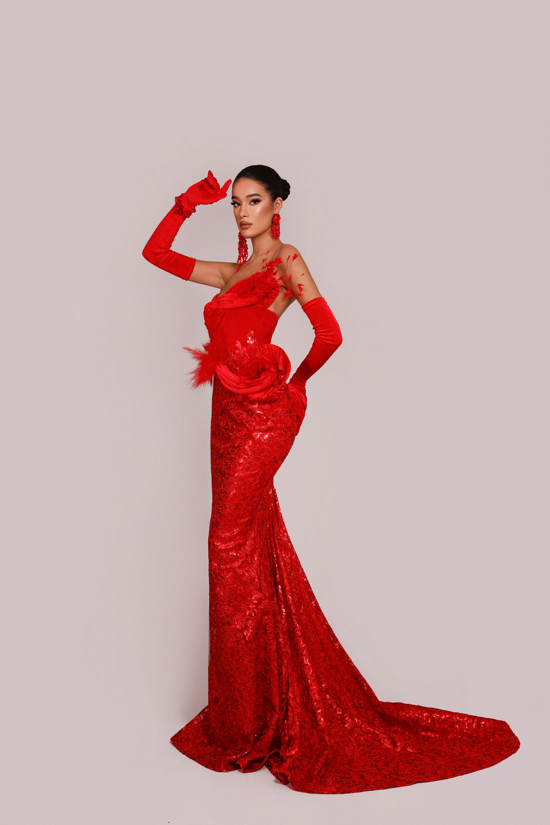 Woman in a red evening gown with a long train on a light gray background