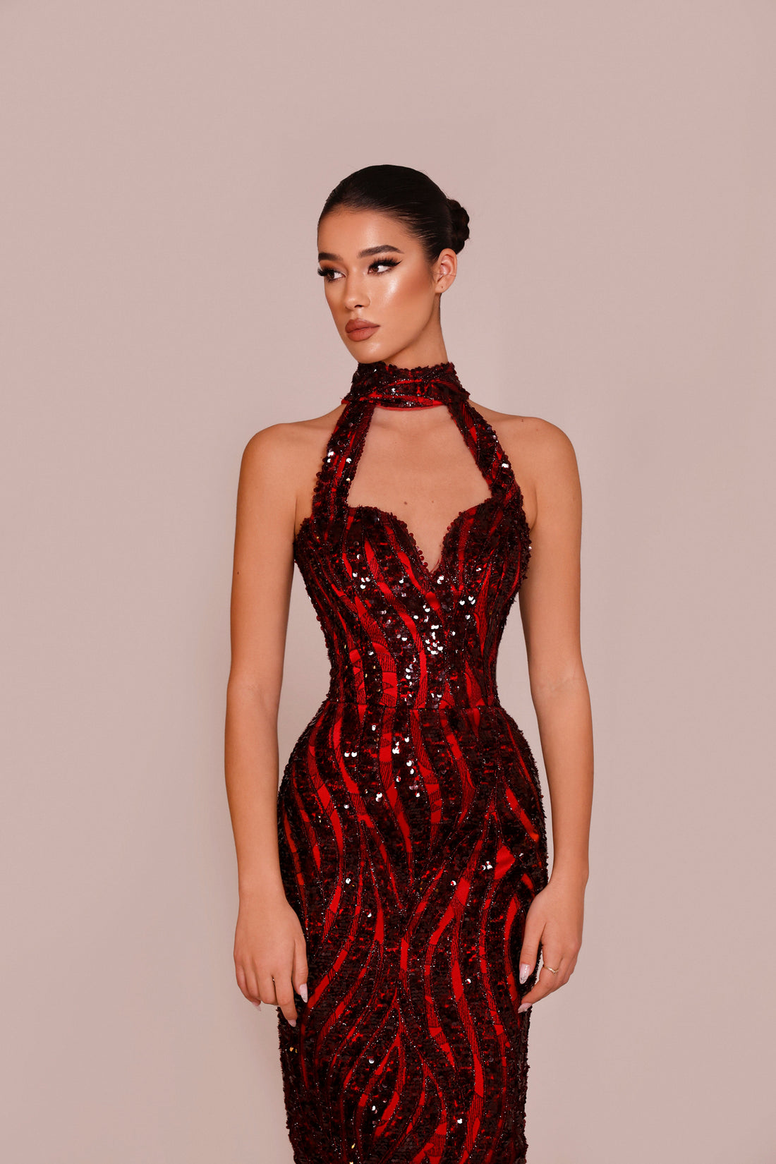 Woman wearing a red and black sequin dress against a beige background